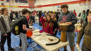 Gym filled with students who are checking out information tables about clubs at the school