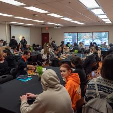 Large group of students, elders, community members and staff gathered in a room sitting at tables